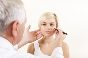 doctor male plastic surgeon with patient examine woman, draw on face